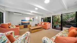 A modern living room with a flat-screen TV, orange sofas, and a wooden coffee table.