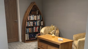 Ein Zimmer mit einem Holztisch, einem Bücherregal und zwei Sesseln.