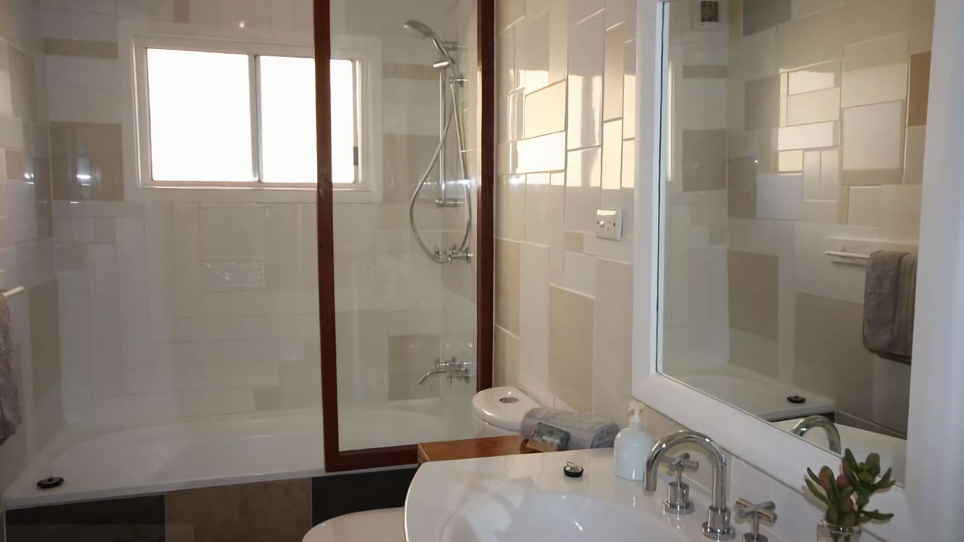 Une salle de bain moderne avec une douche à parois de verre, des toilettes et un lavabo agrémenté d’un grand miroir.