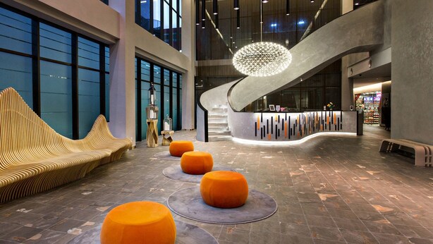 A modern lobby with a curved reception desk, a unique wooden bench, and orange seating areas. - Q Stay at Hotel Damansara (Petaling Jaya)
