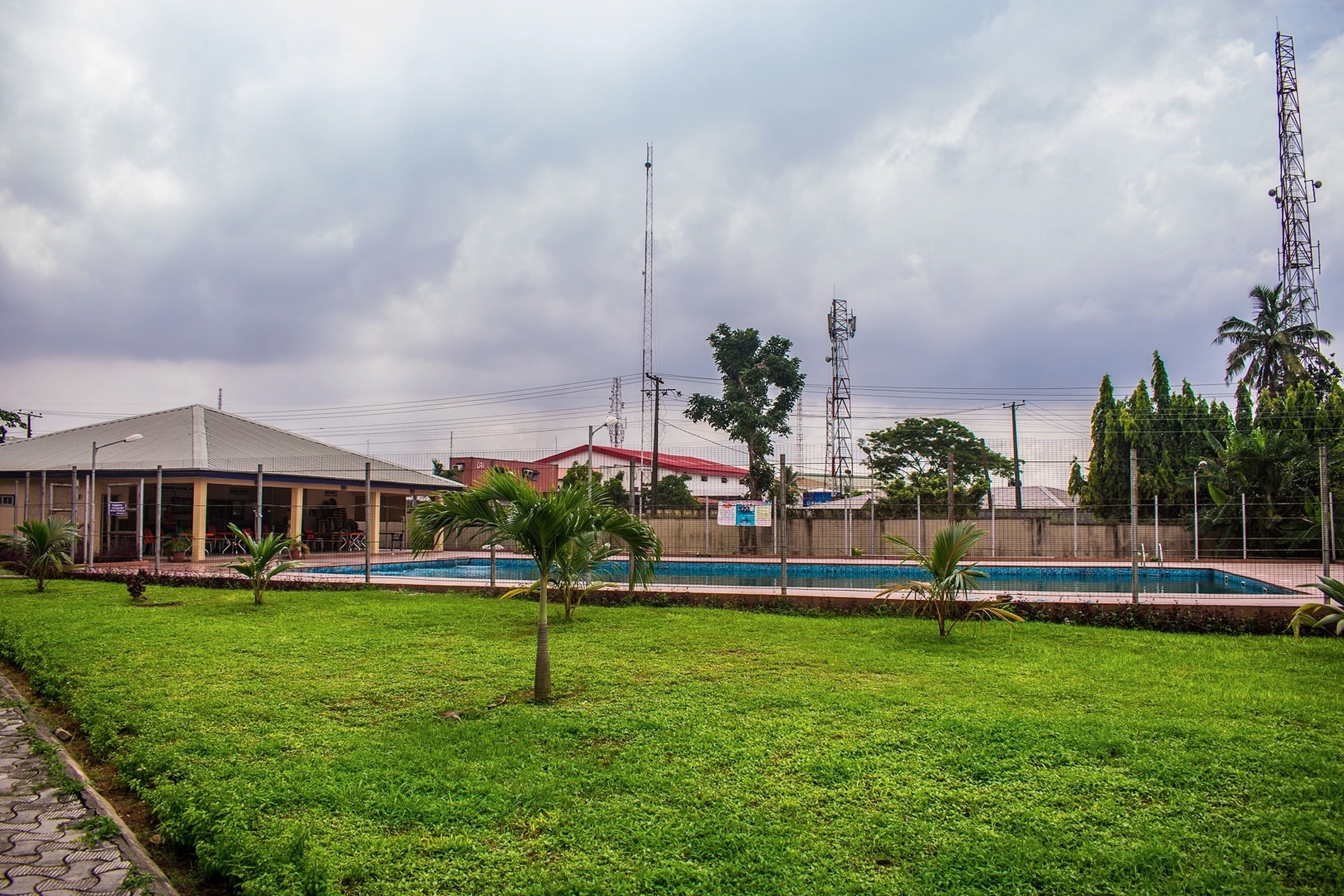 A swimming pool surrounded by a grassy area with a building in the background.