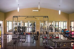 A gym with mirrored walls, various exercise equipment, and large windows allowing natural light. - DBI Guest House (Lagos)