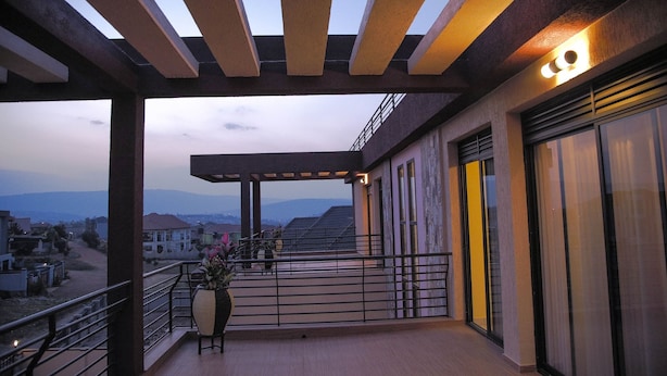 Ein Balkon mit einer Pergola, einem Blumentopf und Blick auf entfernte Häuser.