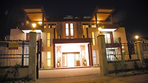 Ein modernes Gebäude mit geschlossenem Eingang, großen Fenstern und einer gut beleuchteten Fassade bei Nacht.