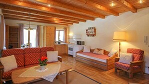 Un salon confortable avec un plancher et des meubles en bois, un coin cuisine équipé d’une cuisinière et d’un four à micro-ondes, et une table à manger avec des chaises.