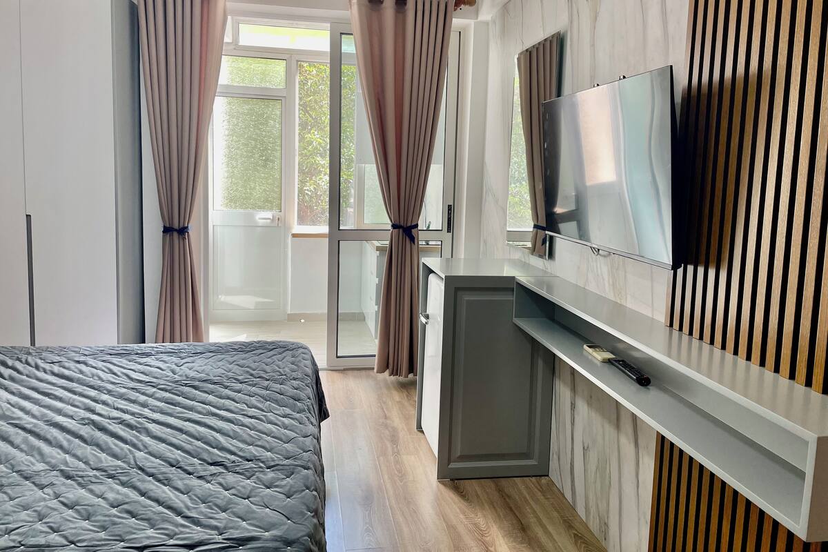 A modern bedroom with a bed, a TV, and a desk.