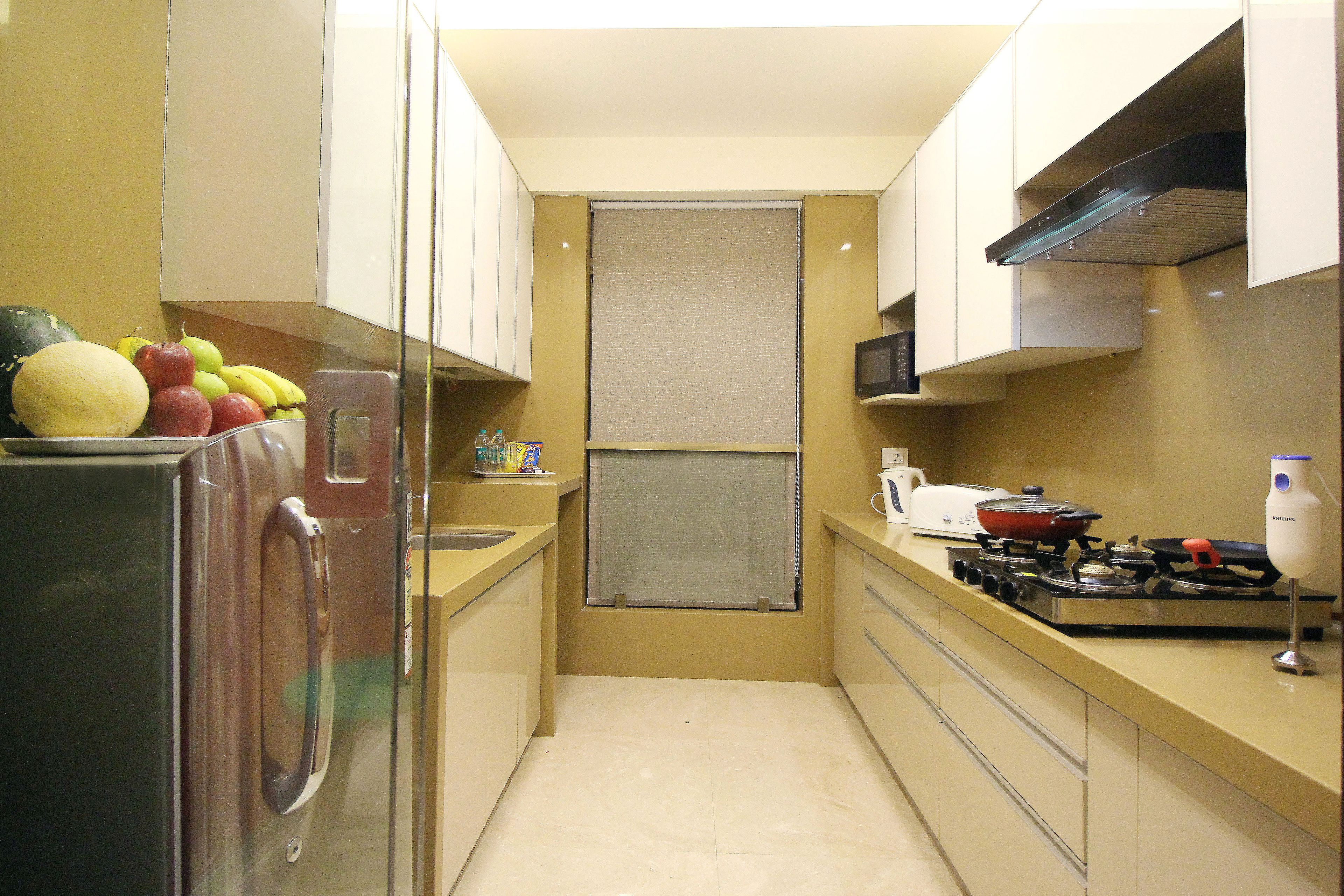 A compact kitchen with a refrigerator, stove, microwave, and a small window.