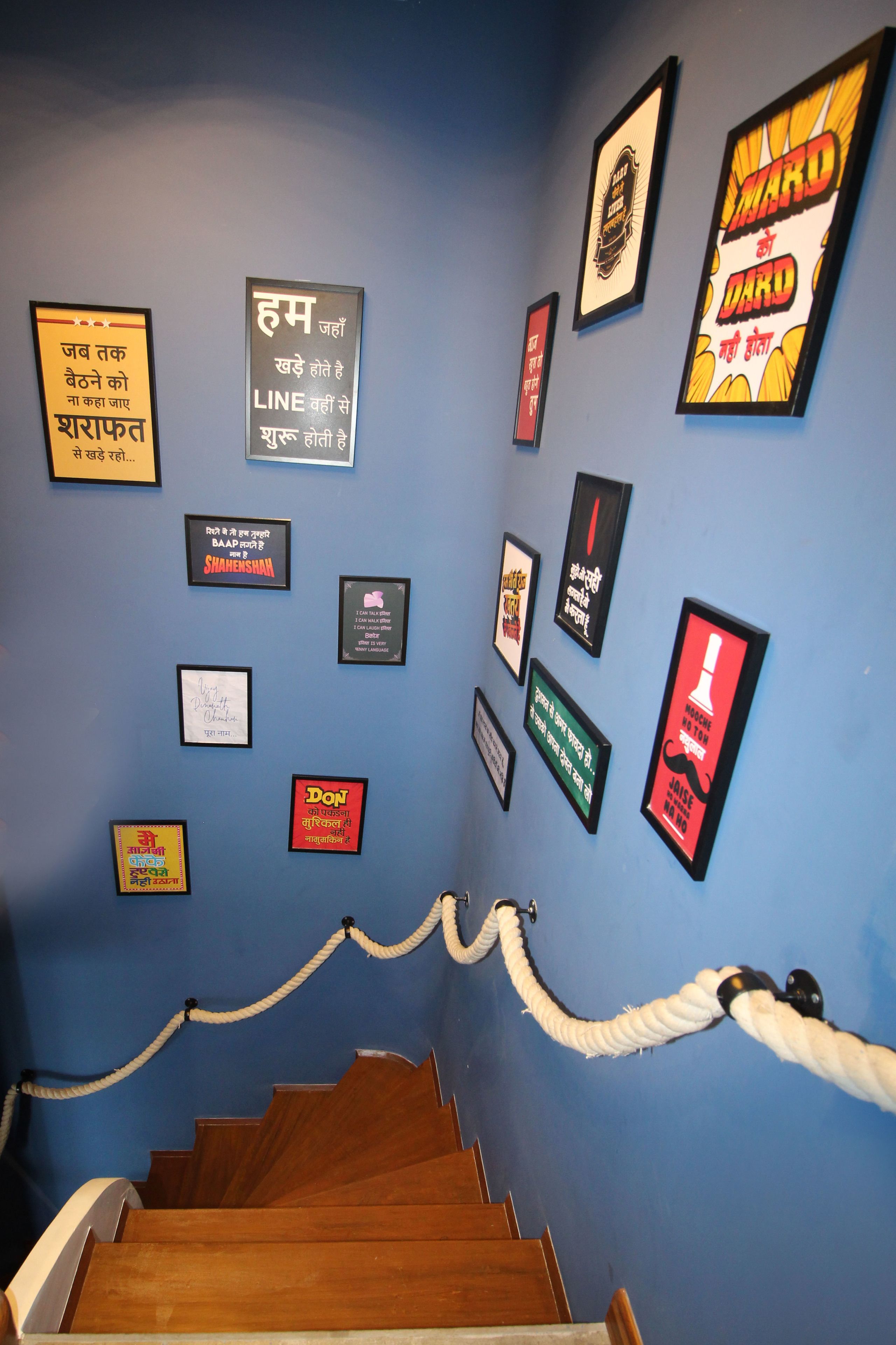 A staircase with a rope barrier and various framed quotes on the wall.