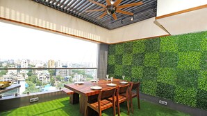 A dining area with a wooden table and chairs, a green wall, and a city view. - Theory9 Premium Serviced Apartments Khar (Mumbai)