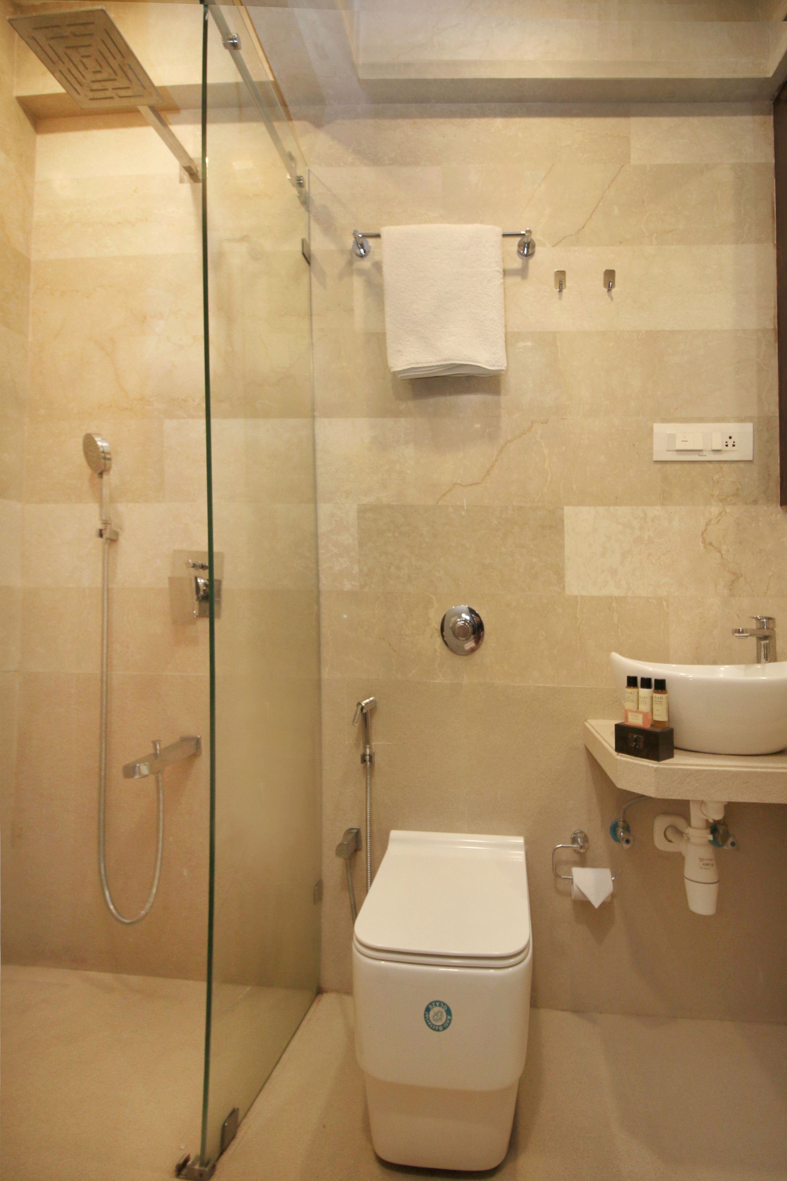 Une salle de bain avec une douche à parois de verre, des toilettes et un lavabo équipé de produits de toilette.