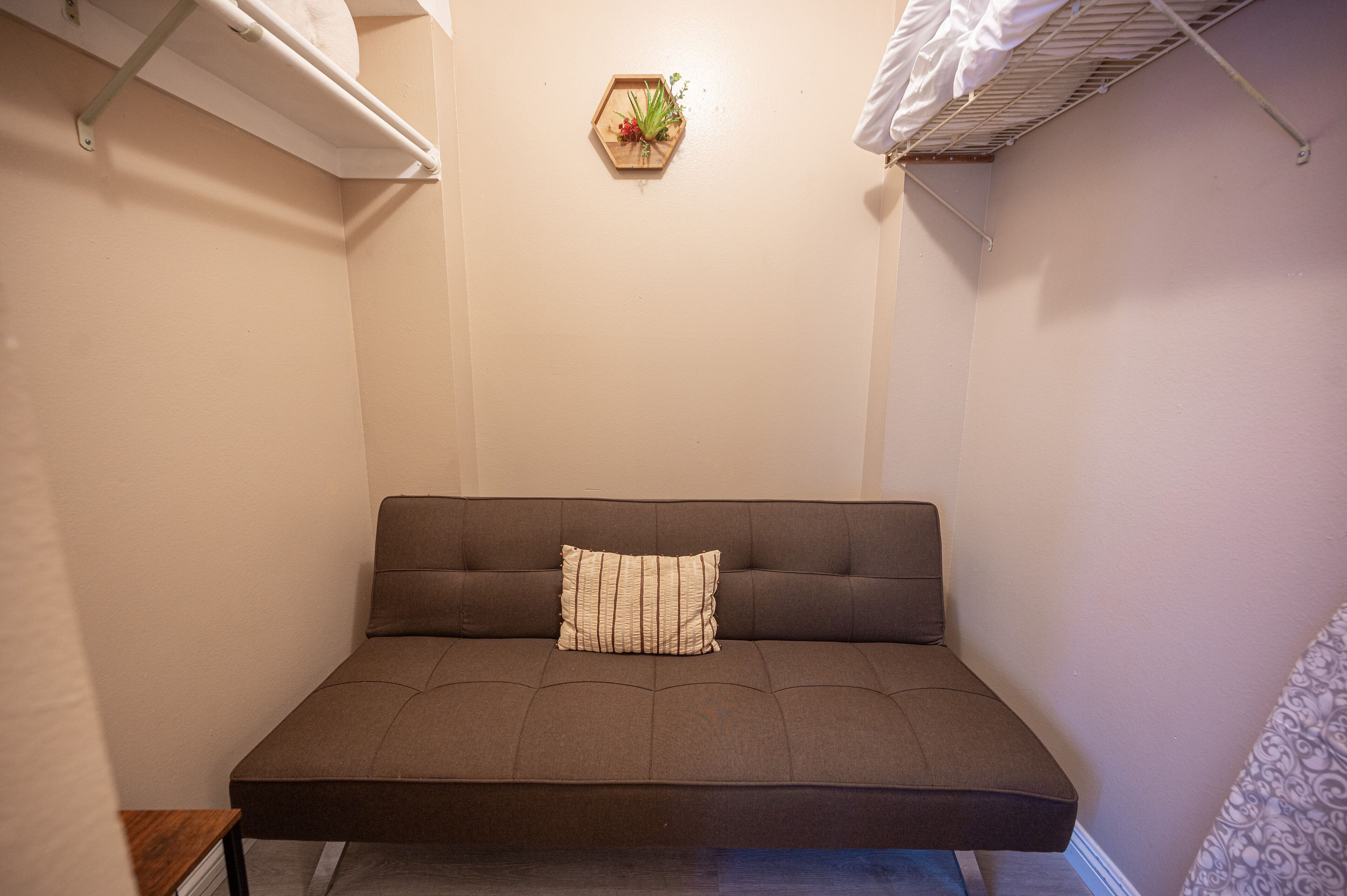 A small, cozy room with a single brown sofa and a decorative hexagonal wall hanging.