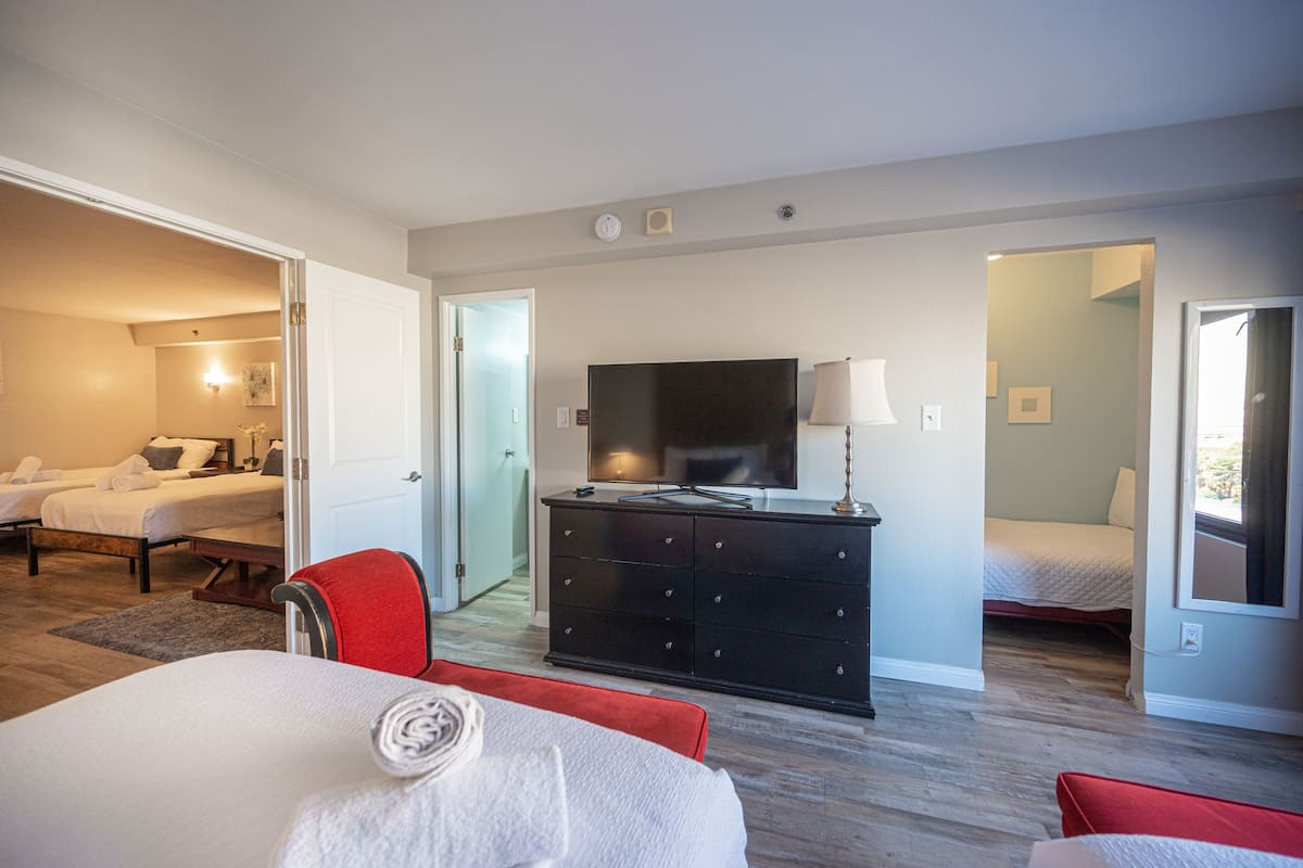 A hotel room with a bed, a TV, a dresser, and a red chair.