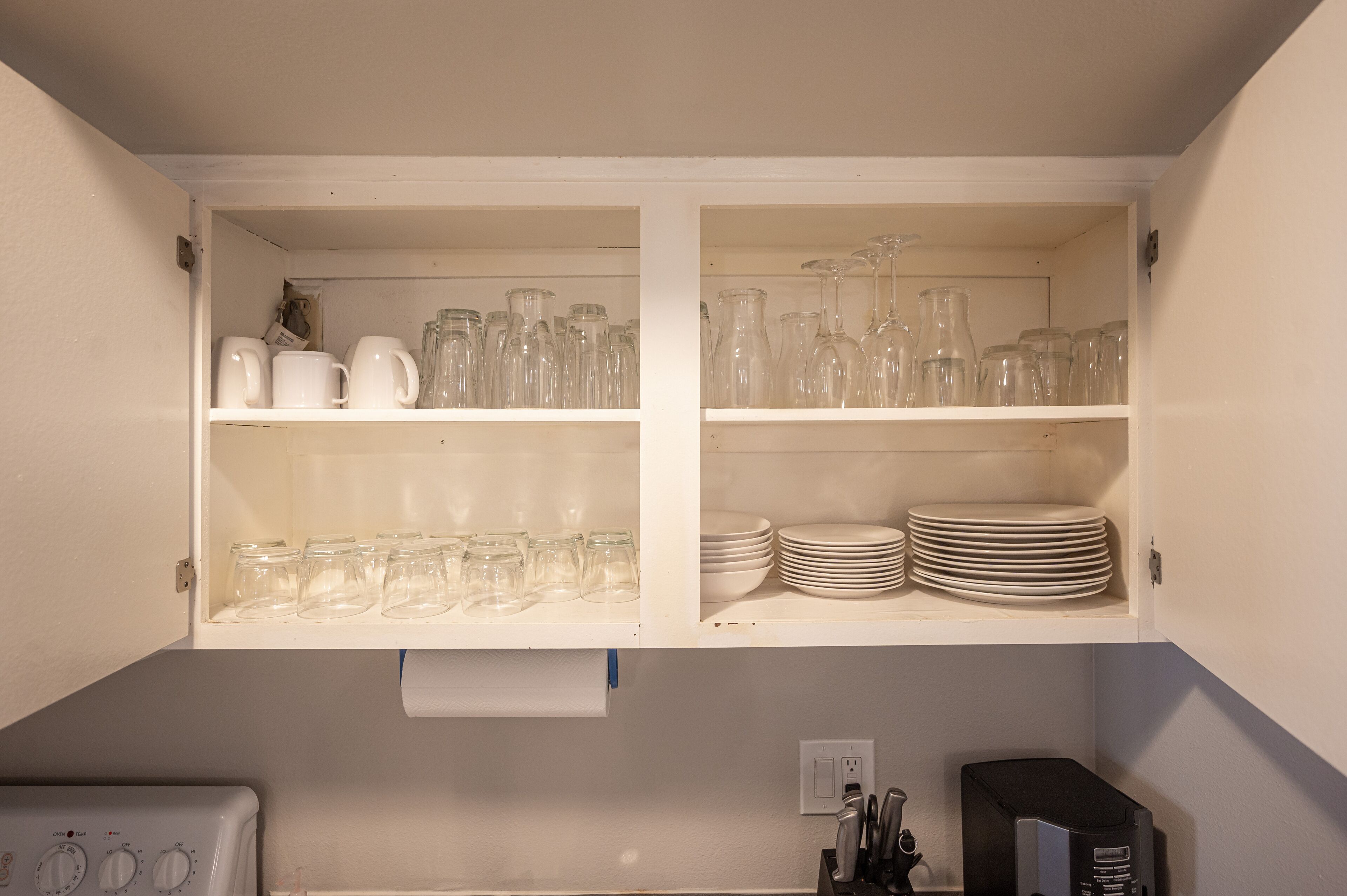 A kitchen with white cabinets, a washing machine, and a coffee maker.