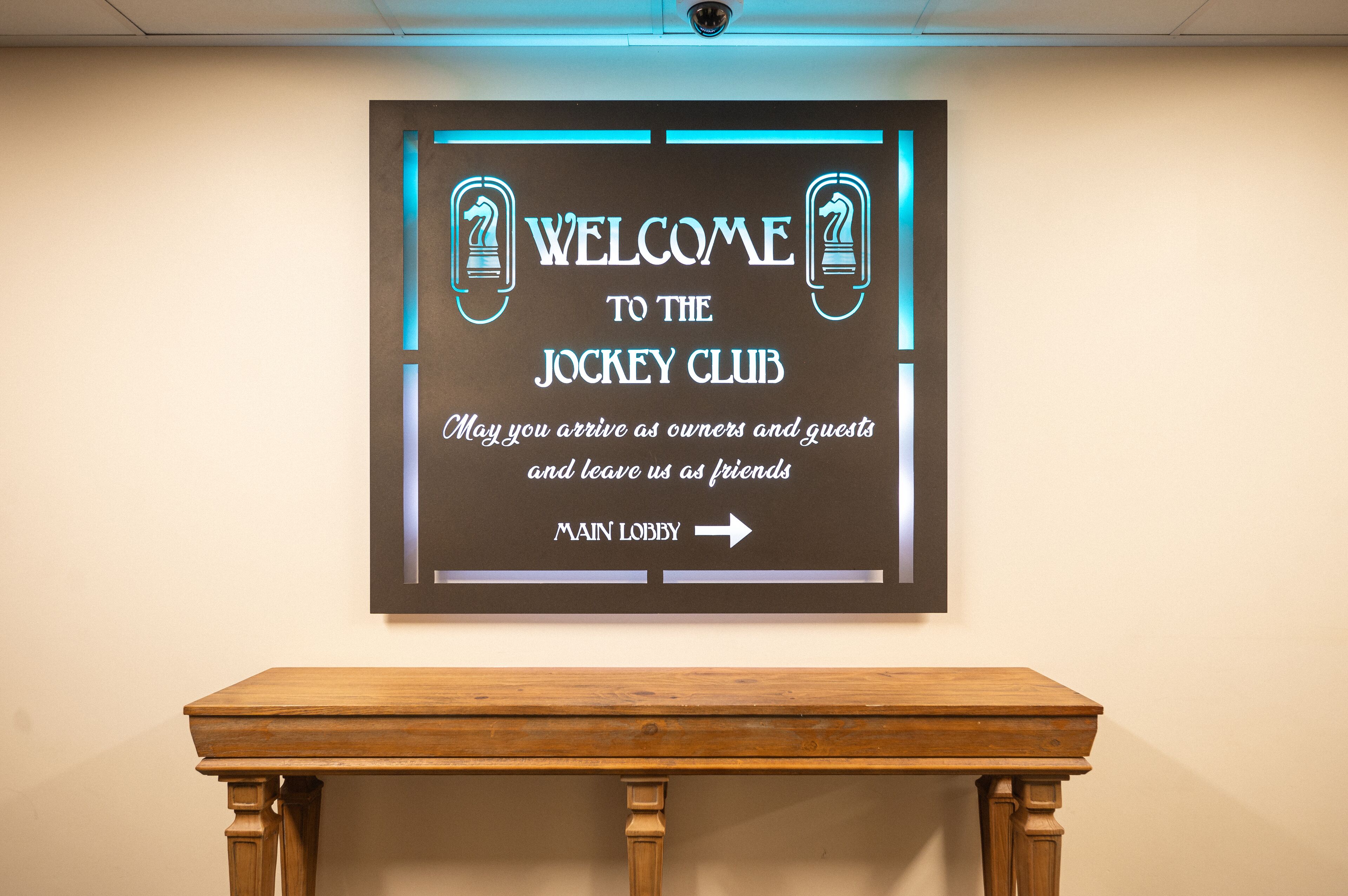 A welcome sign for the jockey club with an arrow pointing to the main lobby.