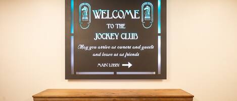 A welcome sign for the jockey club with an arrow pointing to the main lobby.