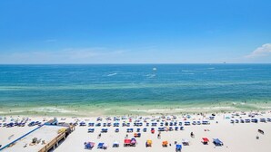A beach with numerous umbrellas and people. - Seawind 1402 | Updated condo with perfect beach view and walk to dine, shop, more! (Gulf Shores)