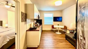 Ein kleines Hotelzimmer mit einer Küchenzeile, einem Essbereich und einem Bett.