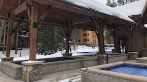 Ein überdachter Außenbereich mit Pool, Holzbalken und einer Steinsitzbank.