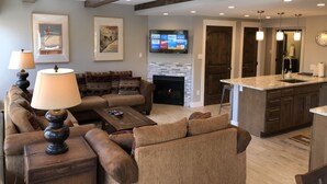 Ein modernes Wohnzimmer mit Kamin, Fernseher und Küchenbereich mit Bar.