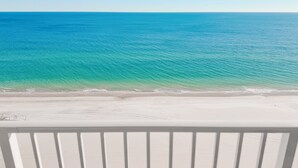 Blick auf einen Strand mit klarem türkisblauem Wasser und weißem Sand.