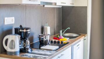 Una cocina moderna con cafetera, una olla, tabla de cortar y verduras frescas.