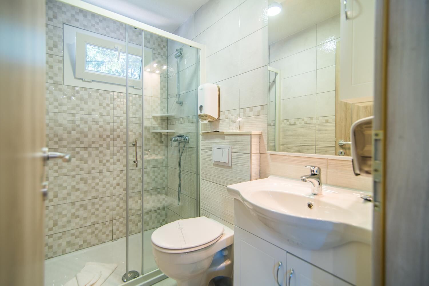 Un baño moderno con ducha cubierta por vidrio, un lavamanos blanco y un inodoro.