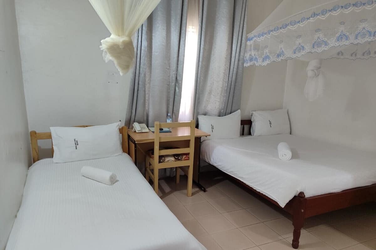 A hotel room with two single beds, a wooden desk, a chair, and a telephone.