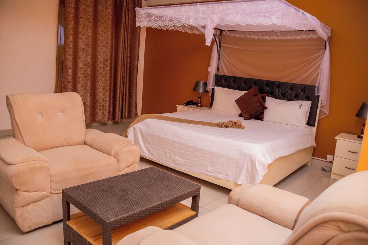 A bedroom with a bed, a chair, a table, and a nightstand.