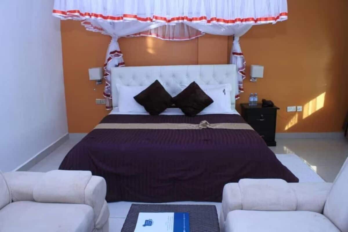 A bedroom with a bed, two bedside tables, a nightstand, and a chair.