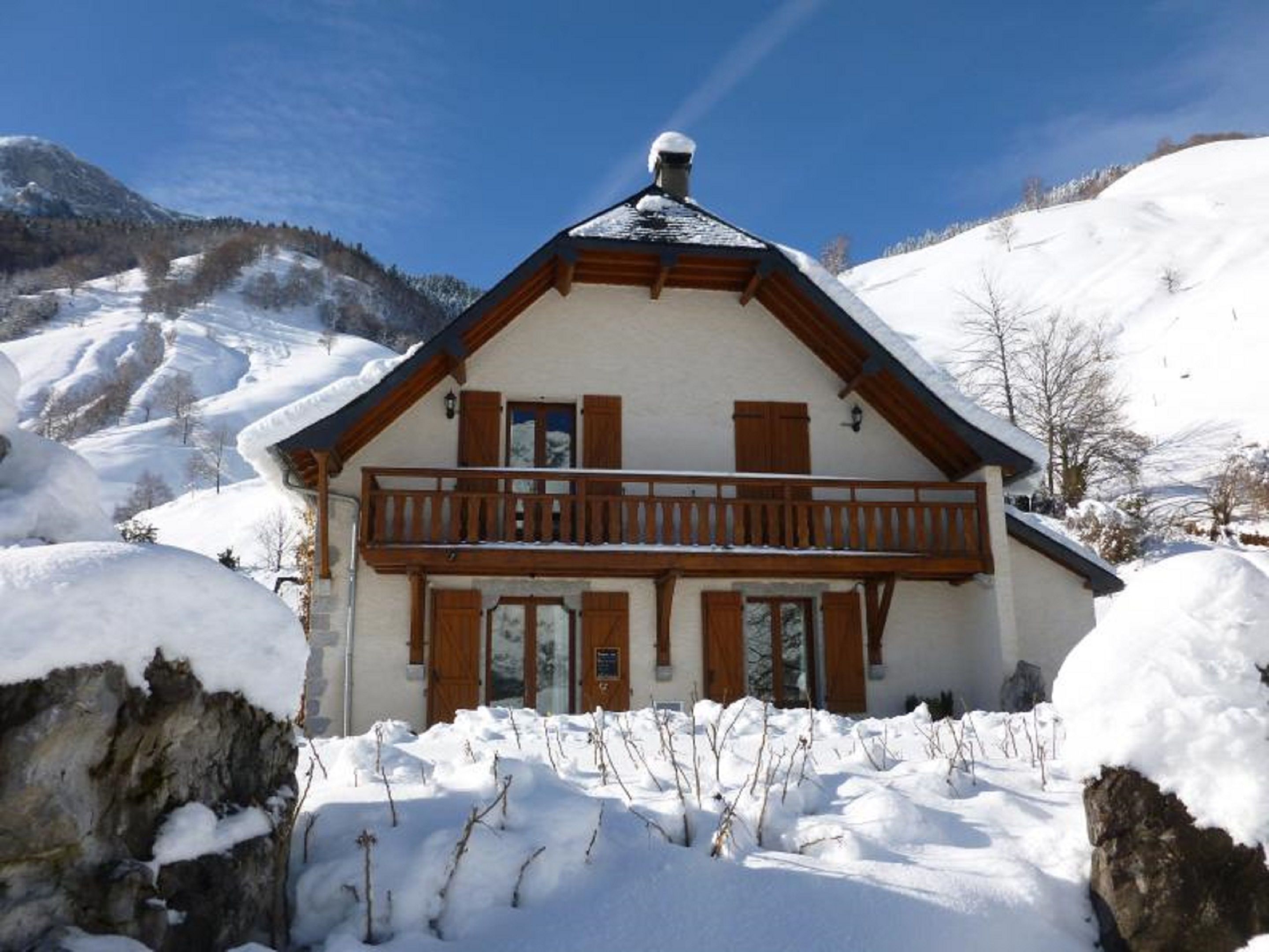 Een chalet met een houten balkon, omgeven door met sneeuw bedekte bergen.