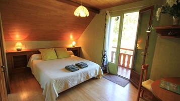 A bedroom with a bed, bedside lamps, a wooden ceiling, and a door leading to an outdoor area.