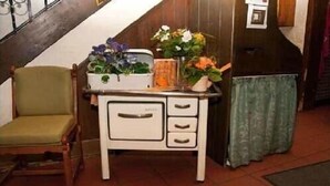 Um quarto com uma cadeira de madeira, uma cômoda branca com gavetas e uma escada ao fundo.