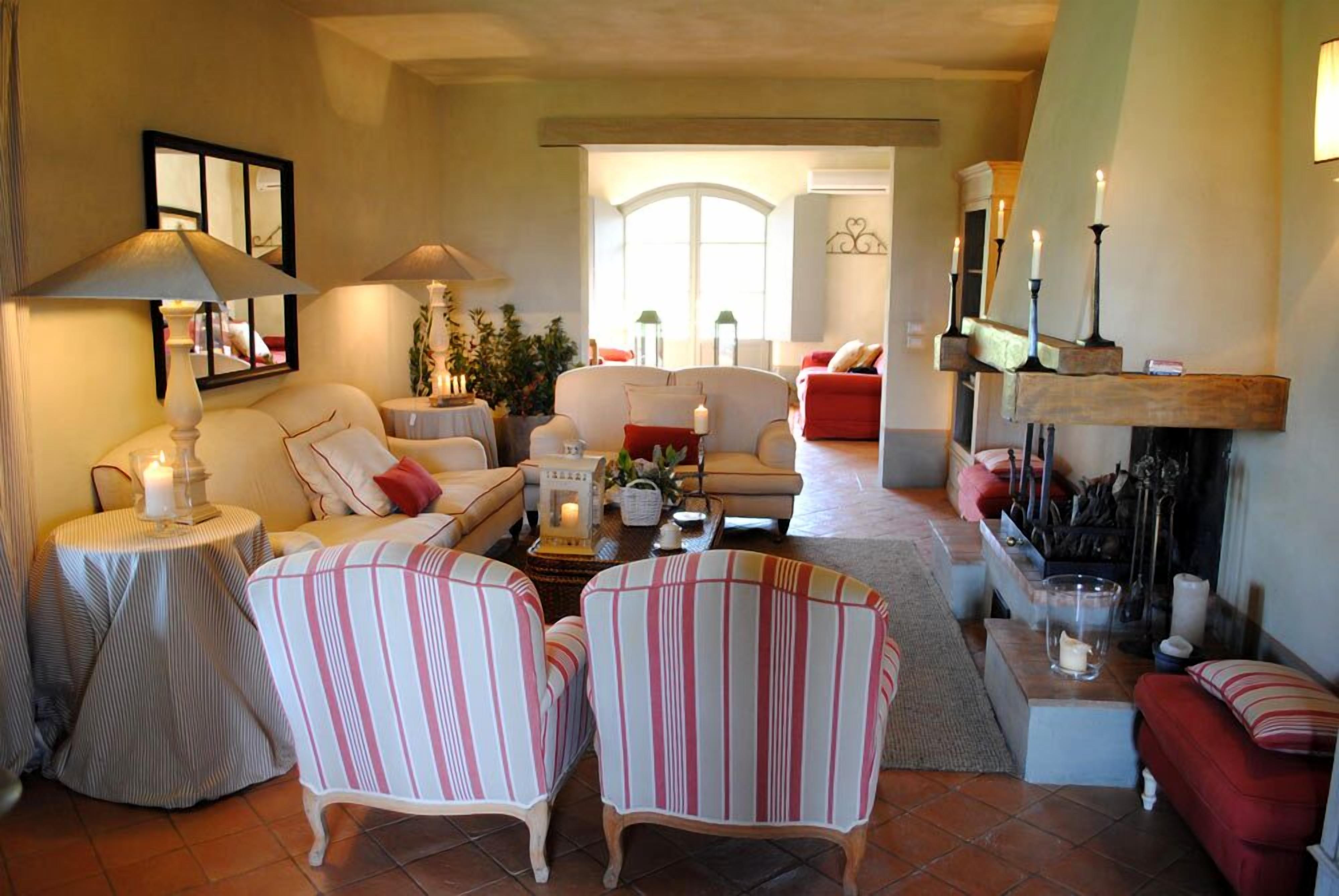 A cozy living room with striped armchairs, a sofa, and a fireplace.