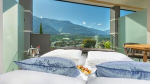 Habitación de hotel moderna con una cama grande, una mesa de comedor y vistas a montañas.