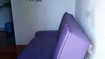 Un canapé violet dans une pièce dont le mur est décoré de motifs floraux.