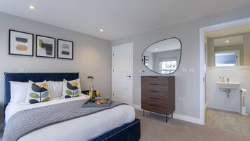 Un dormitorio moderno con una cama grande, un tocador, un espejo y obras de arte en la pared.