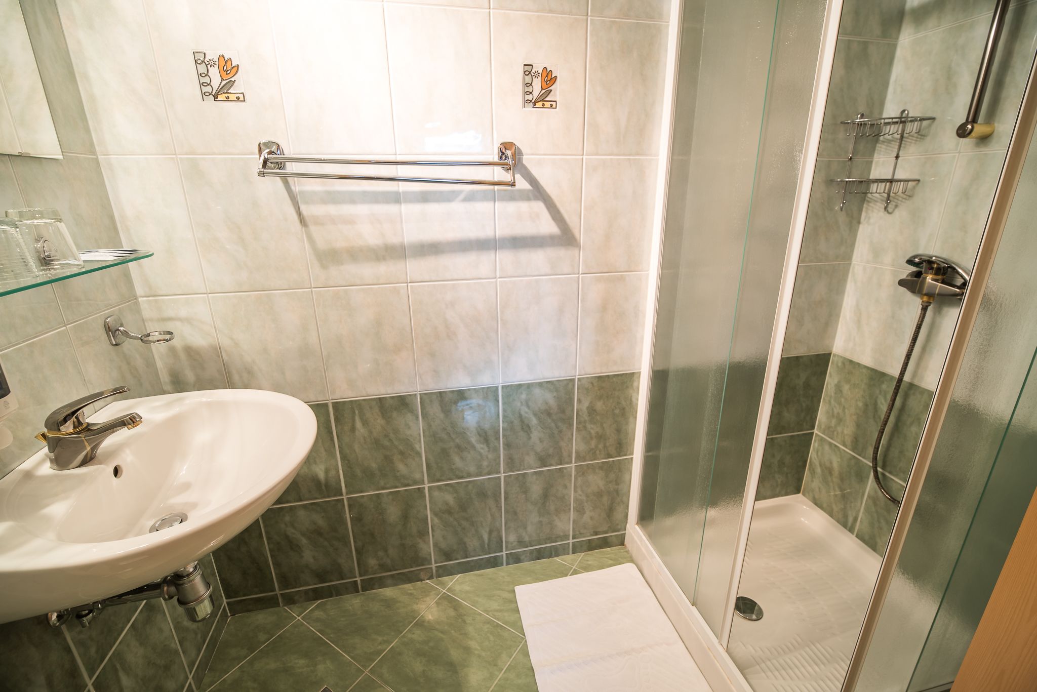 A bathroom with a sink, a glass shower enclosure, and a towel rack.