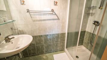 A bathroom with a sink, a glass shower enclosure, and a towel rack.