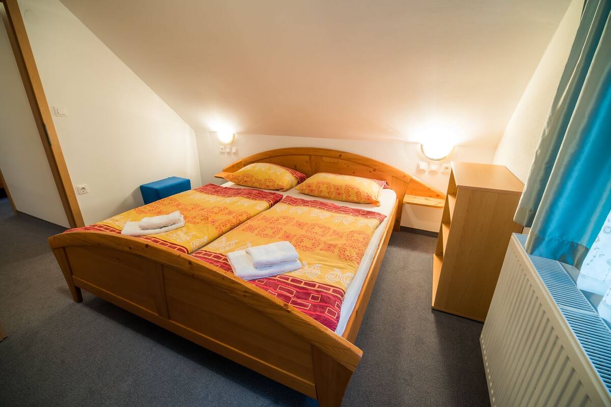 A bedroom with a wooden bed, two bedside tables, a blue nightstand, and a radiator.