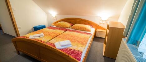 Un dormitorio con una cama de madera, dos mesitas de noche, una mesita de noche azul y un radiador.