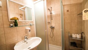A bathroom with a glass-enclosed shower, a sink, and a mirror.
