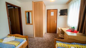 A hotel room with two wooden beds, a desk with a chair, a television, and a mirror.