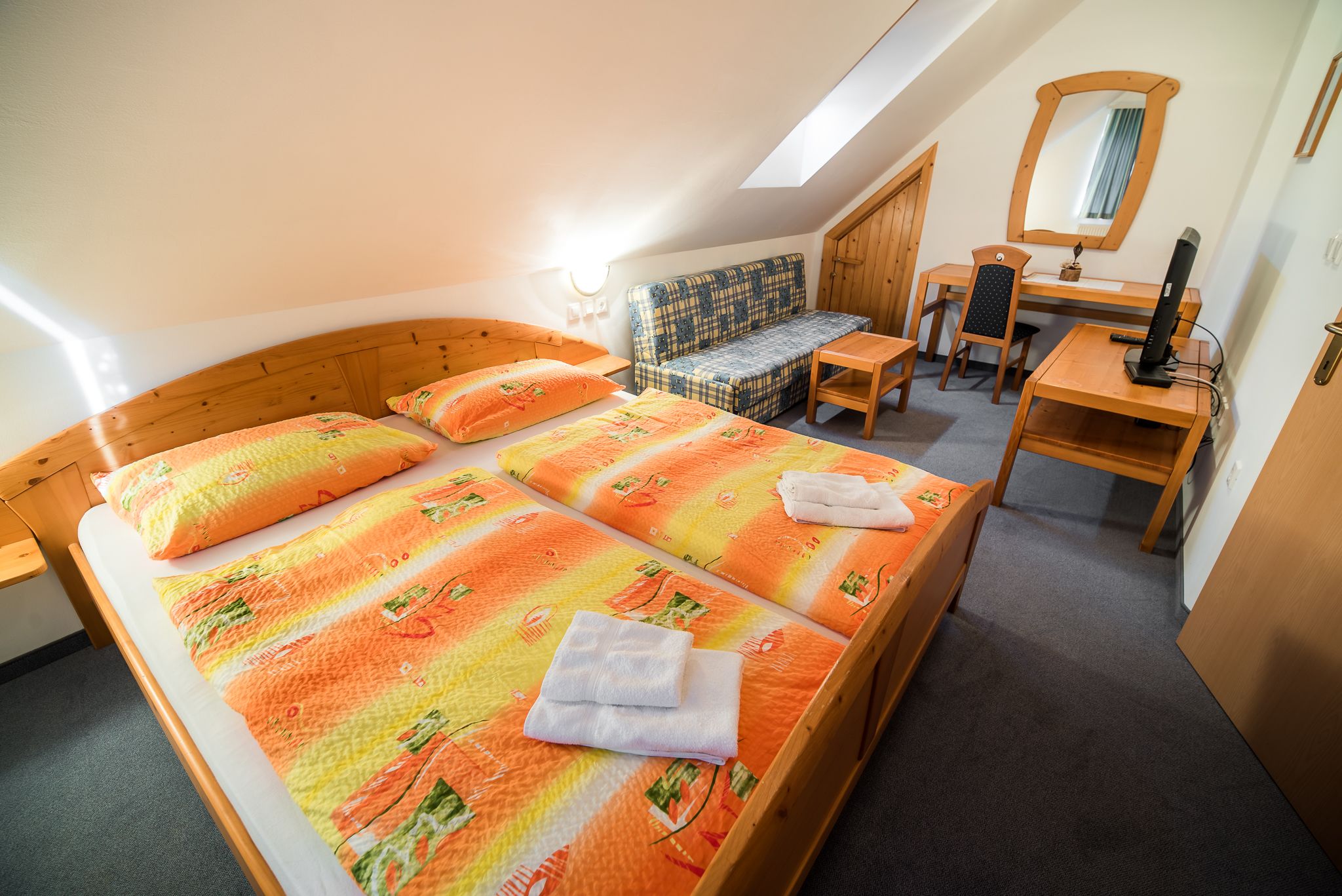 A bedroom with two beds, a desk, a chair, and a small sofa.