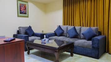 A living room with a sofa, a coffee table, a remote control, and a framed picture on the wall.