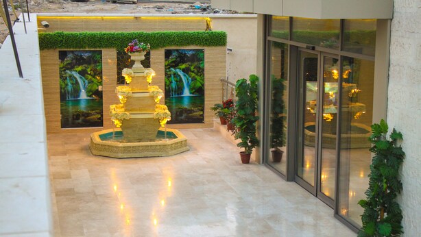 A lobby with a decorative fountain, potted plants, and large framed pictures of waterfalls. - Qaser AlSultan Hotel Suites (Amman)