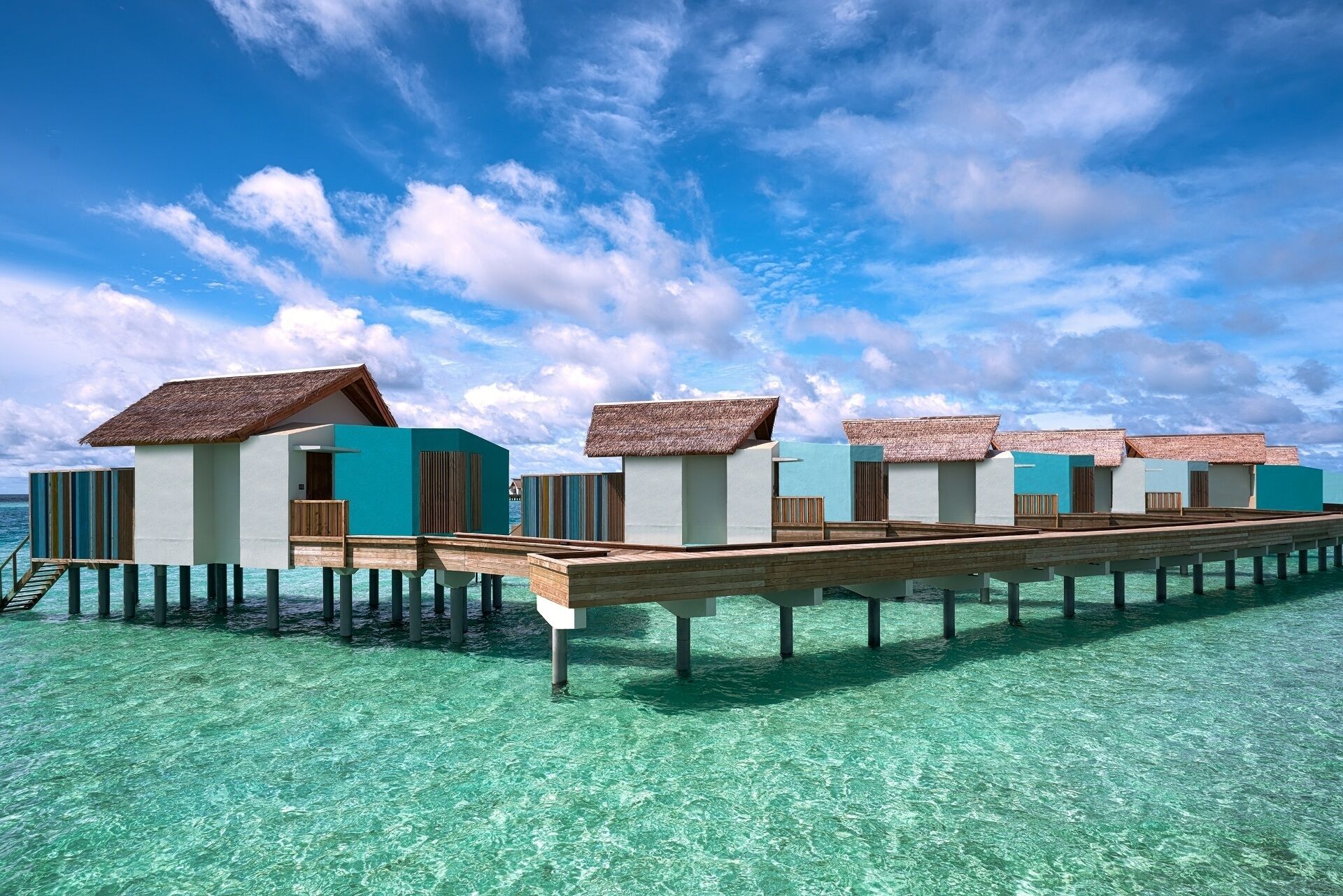 Bungalow sull'acqua con tetti di paglia, passerelle in legno e acque cristalline color turchese.
