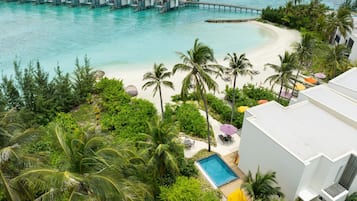 A resort with overwater bungalows, a pool, and lush greenery.