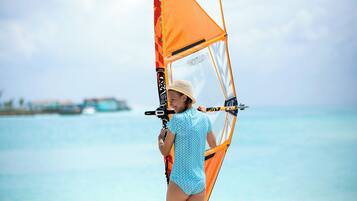 Una persona practicando windsurf con vistas claras al océano y una costa lejana.