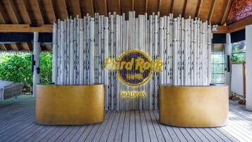 A wooden ceiling with a decorative wall featuring vertical columns and a logo for 'Hard Rock Hotel Maldives'.