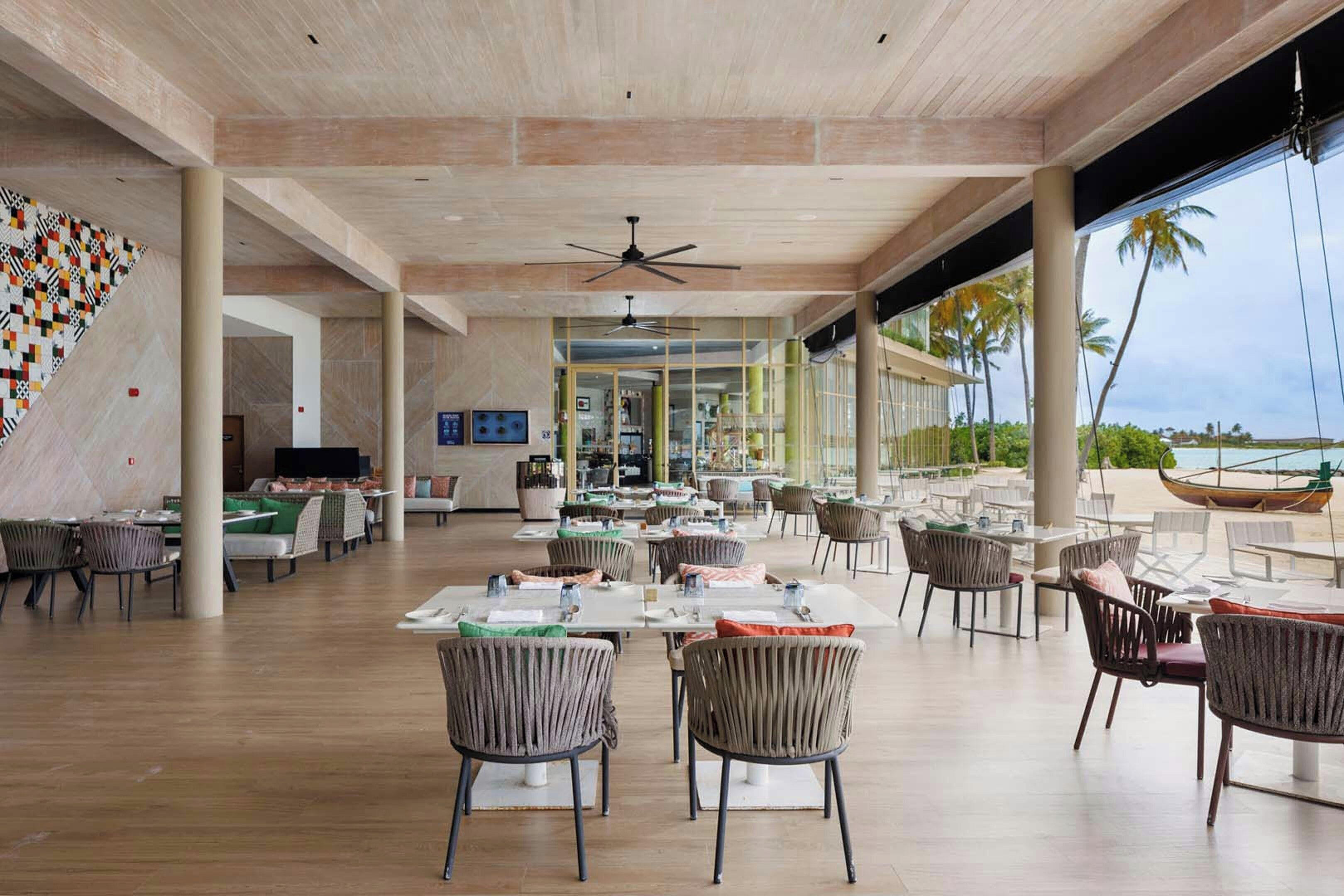 Un comedor interior amplio con techos altos, ventanas grandes y vistas a la playa.